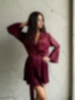 Vínový sametový župan s páskem v pase, focený na modelce u betonové stěny.