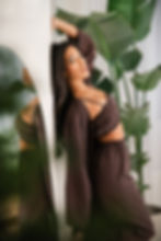 Hnědé tencelové pyžamo s dlouhým topem a širokými kalhotami, focené u interiérové rostliny.