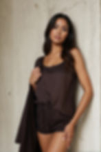 Hnědé tencelové dámské pyžamo s topem na ramínka a dlouhými kalhotami, focené u betonové stěny.