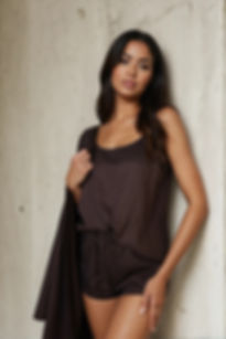 Hnědé tencelové dámské pyžamo s topem na ramínka a dlouhými kalhotami, focené u betonové stěny.