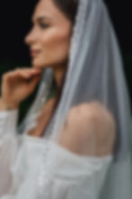 Žena v elegantních svatebních šatech s dlouhým svatebním závojem zdobeným perličkami a flitry