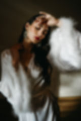 Žena v hedvábném županu s širokými rukávy a labutěnkou, pózující v elegantním interiéru.