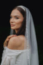 Detail svatebního závoje s drobnými perličkami a třpytivými flitry, uchyceného v jemném tylu svatebního závoje.