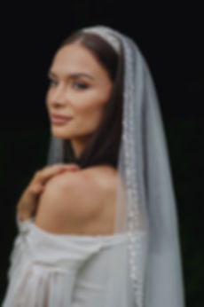 Detail svatebního závoje s drobnými perličkami a třpytivými flitry, uchyceného v jemném tylu svatebního závoje.